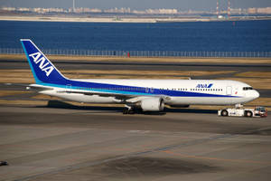 ANA飛機在機場停機坪上被拖行，靠近水和城市。