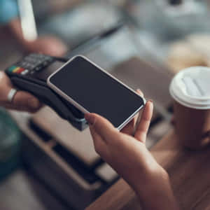 人在咖啡店櫃檯使用智能手機付款。