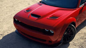 陽光下碎石地上的紅色Dodge Challenger RT跑車。