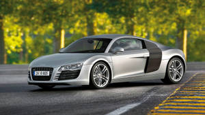 銀色奧迪R8跑車在鋪砌的道路上，背景有綠樹。 — Audi R8 GIF 壁紙