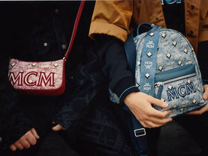 兩個人手持帶有鉚釘和標誌的MCM品牌手袋。