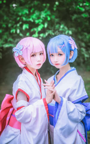 兩位身穿角色扮演服裝、頭髮粉紅和藍色的年輕女性一起站在森林中。 — Galaxy Z Fold 8 壁紙