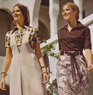兩位穿著1970年代時尚的女性，面帶微笑走在白色拱門下。 — 70年代gif 壁紙