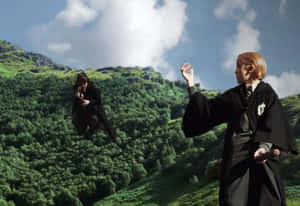 兩位巫師飛越森林覆蓋的山地景觀。 — 霍格華茲 GIF 壁紙