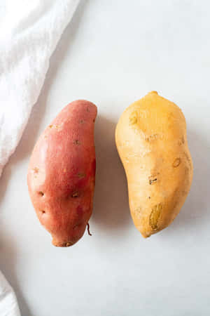 兩個番薯一個紅色一個黃色在白色表面 — iPhone Duo 壁紙