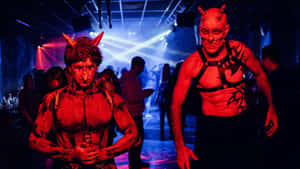 兩個打扮成魔鬼、臉上塗著紅色顏料、頭上有角嘅男人喺夜總會派對上。 — 萬聖節恐怖 壁紙