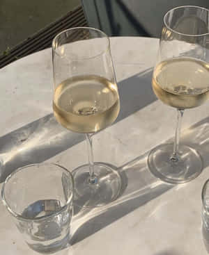 明亮的陽光下，大理石桌上的兩個酒杯和一個水杯。 — Apple Watch 壁紙