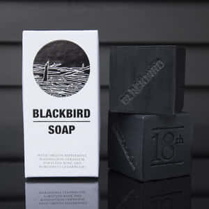 Blackbird Soap 肥皂條和包裝在反光表面上。 — 1:1 壁紙