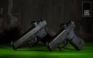 兩把黑色 Glock 手槍帶有綠色發光瞄準器在綠色表面上。