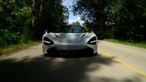 銀色McLaren在森林道路上高速行駛，帶有動態模糊效果。