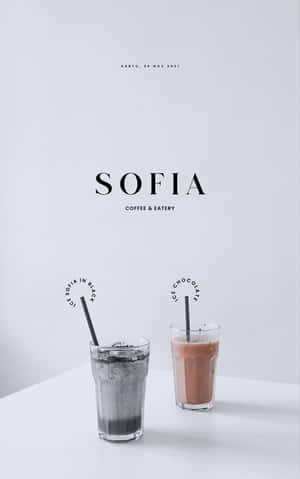 兩杯冰飲，分別標有黑色的ice sofia和ice chocolate，放在帶有咖啡館品牌的白色桌子上。 — 極簡美學 壁紙