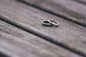 兩枚結婚戒指一起放在木桌上。 — MacBook 壁紙