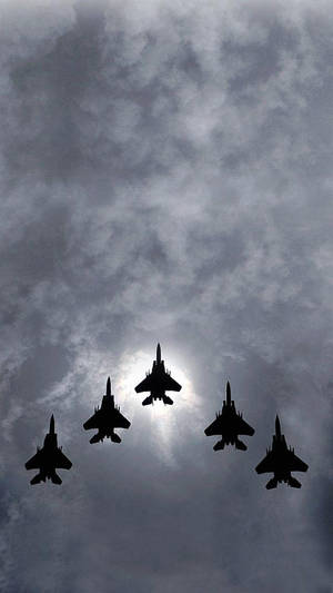 五架戰鬥機在多雲天空中編隊飛行，太陽在身後。