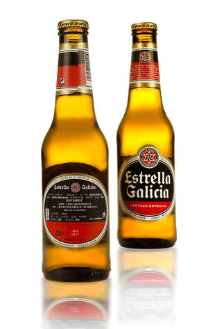 兩瓶Estrella Galicia啤酒，標籤朝前，放在白色反射表面上。