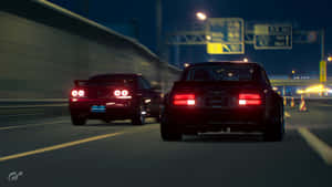 兩輛紅色跑車在夜間高速公路上疾馳，帶有發光的尾燈。 — 午夜 壁紙