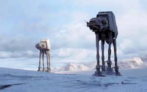 兩部 AT-AT 步行機喺雪地沙漠景觀中，背景有山脈。 — 星際大戰 壁紙