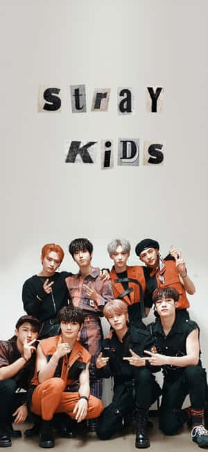 Stray Kids 穿著橙色和黑色服裝在攝影棚擺姿勢的團體照。