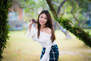 年輕女性在公園裡微笑，背景有長滿苔蘚的樹枝 — 亞洲 壁紙
