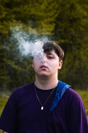 青少年在戶外呼出煙霧，背景是森林。