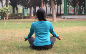 女性在公園草地上盤腿冥想