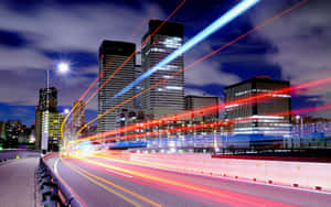 夜間城市高速公路，移動車輛的光跡與發光的摩天大樓。