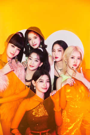 六位身穿橙色服裝的K-pop女性在黃色心形背景的工作室中擺姿勢。 — Vivo Pad6 Pro 壁紙