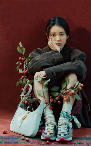 年輕女性穿著時尚服裝，搭配櫻花枝和白色手袋，背景為紅色。