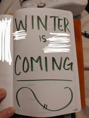 手拿筆記本，「WINTER IS COMING」文字部分被白色塗鴉遮蓋。