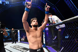 UFC拳手在八角籠內舉臂慶祝勝利。