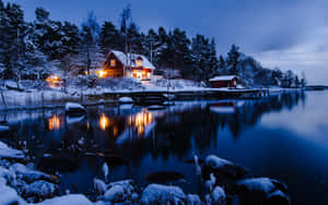 夜晚湖邊雪覆蓋的小屋，溫暖燈光反射在平靜水面上。