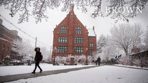 學生在積雪的校園小徑上行走，靠近磚造大學建築。