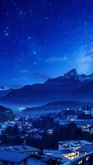 山城在星空夜空下，窗戶發光，山峰積雪。