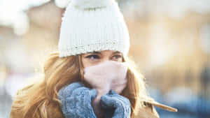 女性戴著冬季帽子和手套在寒冷天氣中遮住嘴巴。