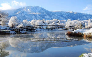 冬季河上雪橋與山巒倒影