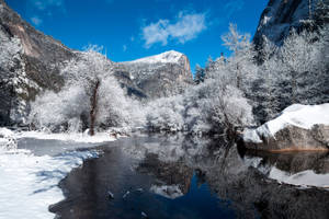 白雪覆蓋的森林，冰封的河流在清澈的藍天下映照著花崗岩懸崖。 — 藍天 壁紙