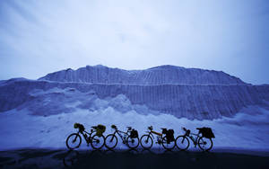 四輛旅行單車在暮色中停放在雪山前。
