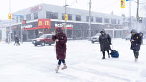 行人在暴風雪中於麥當勞附近的積雪城市街道上行走。