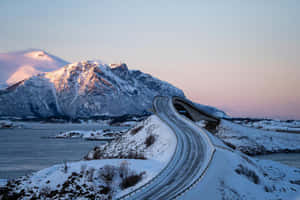 暮色中彎曲越過峽灣的積雪山路