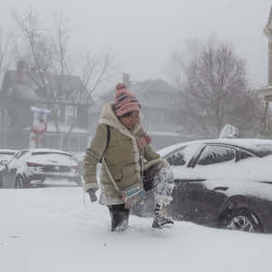冬季風暴期間，有人在深雪中走在停泊的汽車旁邊。