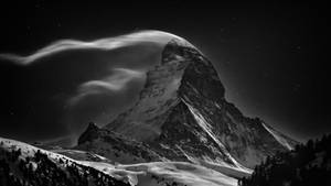 星空下白雪覆蓋的山峰與流動的雲層
