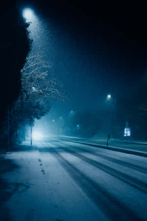 一個人在發光的路燈下，獨自走在積雪的夜街上。