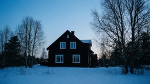一間舒適的木屋，窗戶亮著燈，在雪白的冬日景色中，時值黃昏。