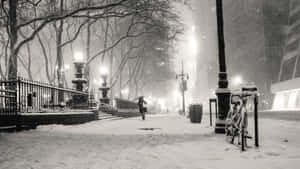 夜晚在街燈下撐傘在雪中行走的人。