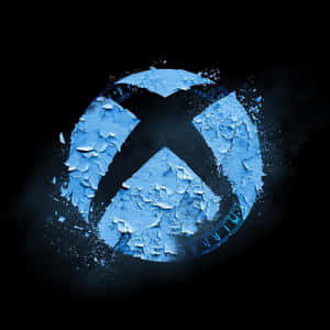 一個發光的破裂藍色Xbox標誌，帶有剝落的油漆和漂浮的碎片，背景為黑色。 — Xbox GIF 壁紙