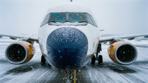 冬季暴風雪中，被雪覆蓋的飛機停在積雪跑道上。