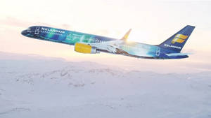 冰島航空飛機在日出時飛越積雪的山脈。