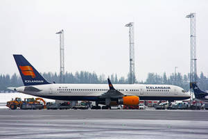 冰島航空飛機停泊在濕滑機場停機坪，背景有地勤車輛和樹林。