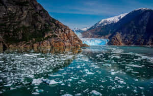 冰川崩解流入冰冷的水域，周圍是岩石山脈 — 湖景 壁紙