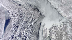 衛星圖像顯示水面上和陸地上的雲、冰和雪。 — 行星 壁紙
