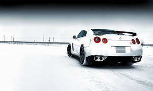 白色日產GT-R跑車在雪路上行駛，冬季風景。